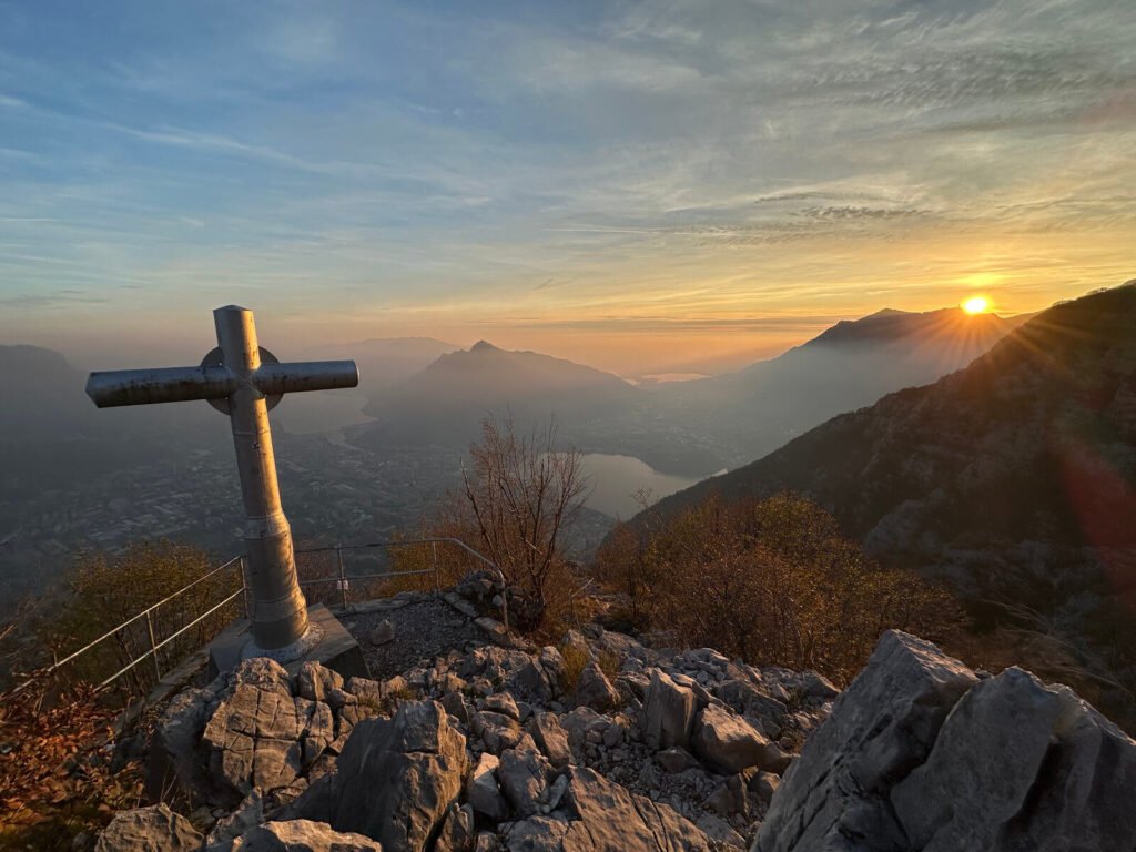 Sunset next to a cross, overlooking a valley. From near Lake Como in Italy